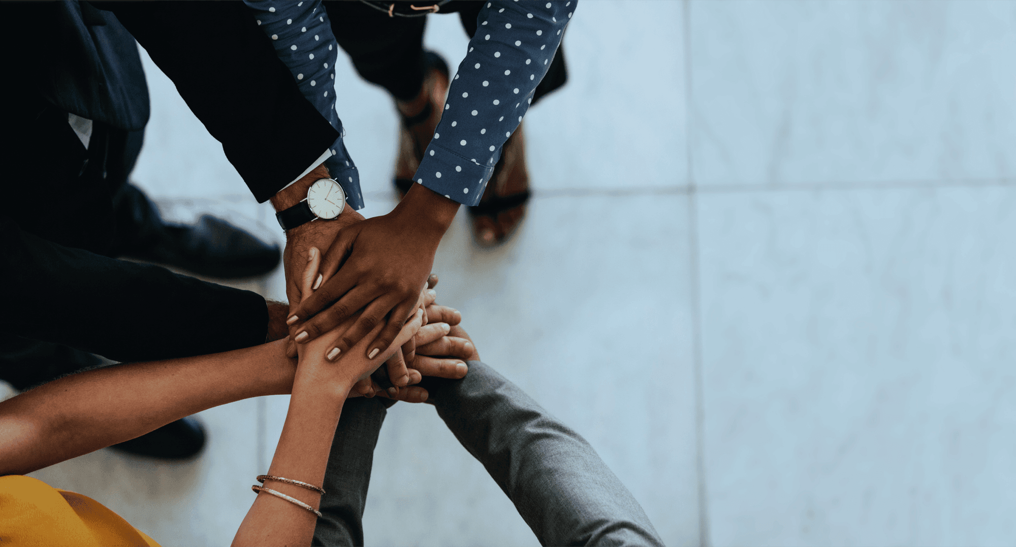 Time diverso com mãos sobrepostas em gesto de união